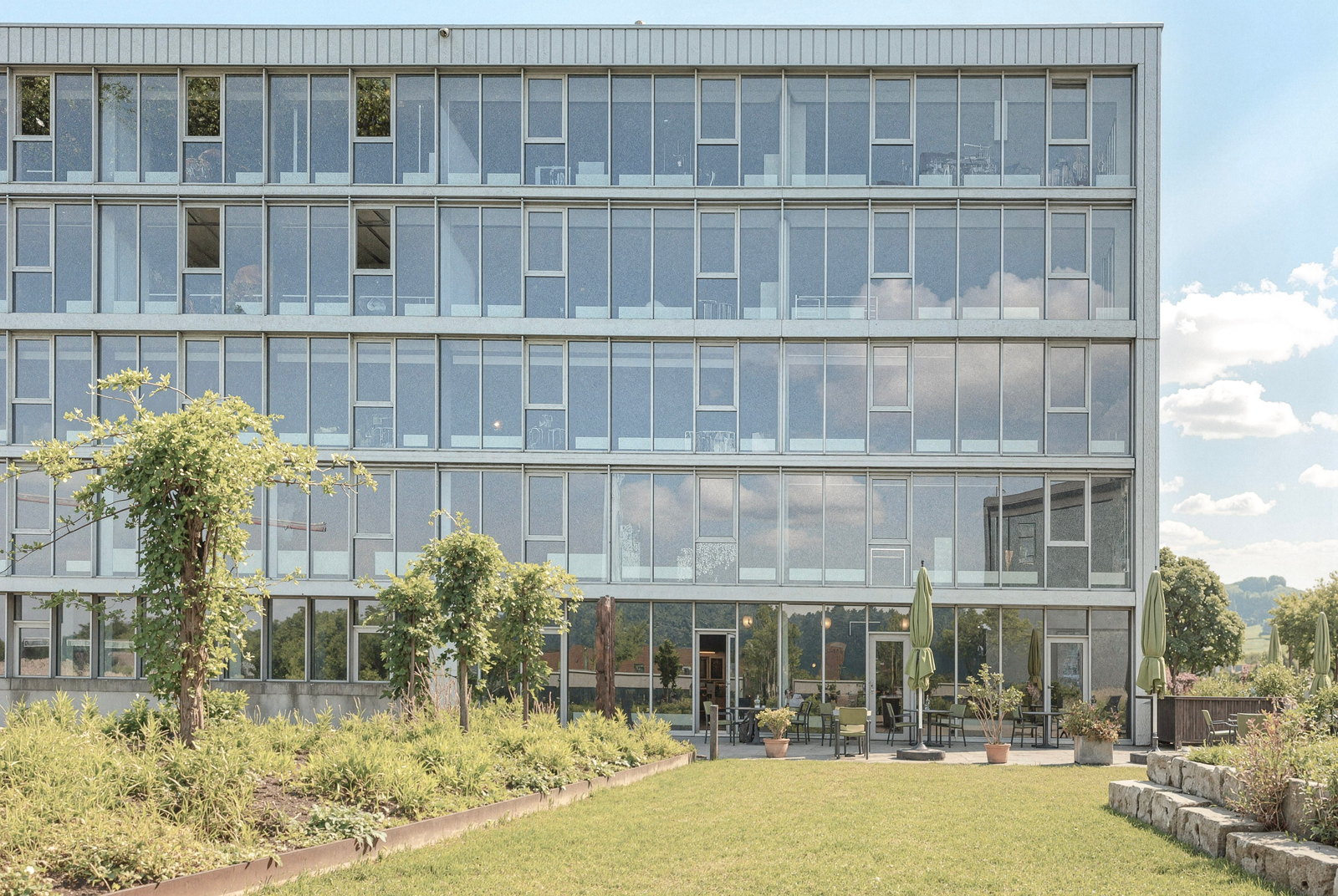 Verglaste Fassade des Bürogebäudes KURT.SG mit begrünter Gartenterrasse